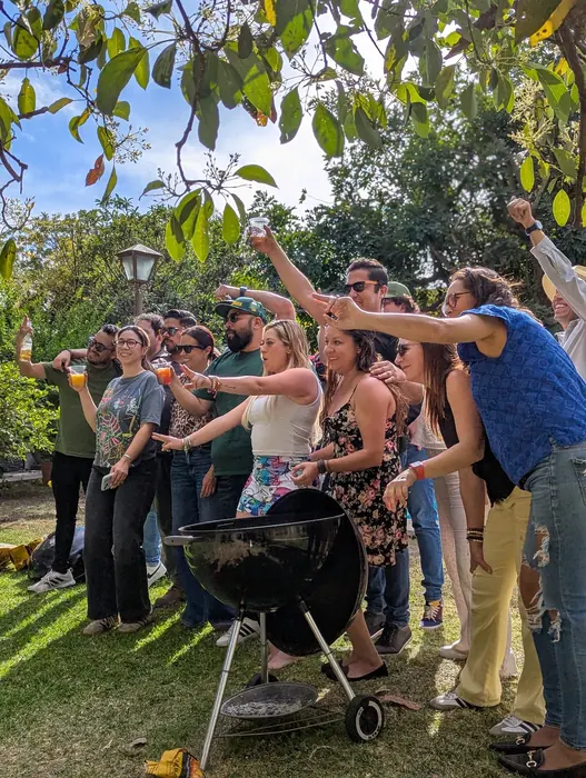 Grupo brindando alrededor de un asador en un jardín