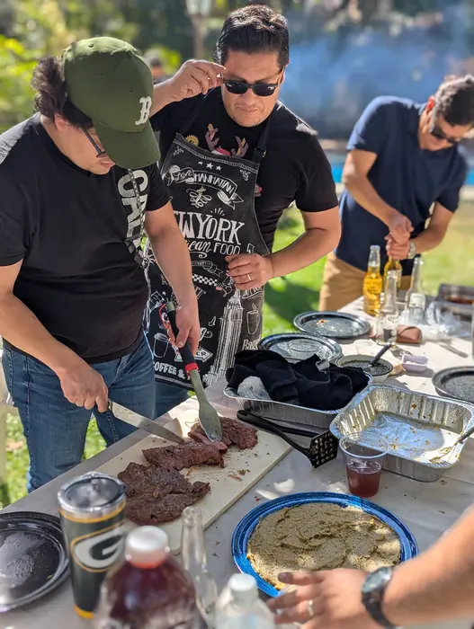 Equipo cortando carne recién asada en una mesa al aire libre