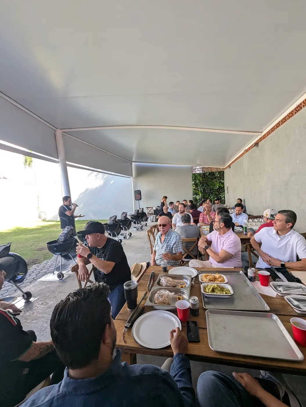 Equipo de trabajo comiendo bajo una carpa después de cocinar al carbón